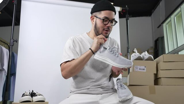 Young attractive Asian man blogger or vlogger looking at camera reviewing product and merchandise. Business online influencer on social media concept.