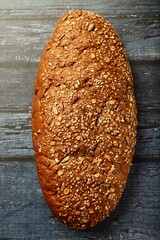 Top view- fresh baked multigrain brown bread on  a wooden kitchen table.