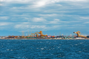 Fototapeta premium Ships under loading in the seaport in the city of Tsawwassen, stormy sea dramatic sky, overcast