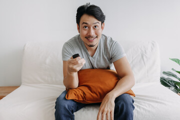 Excited face of asian man watching tv channel in his living room.