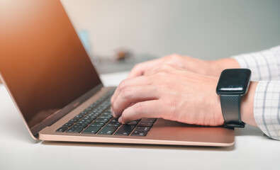 Human hand using laptop with blank screen on table in home interior.