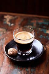 Coffee in glass cup on rustic wooden background
