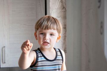 Portrait of a little boy of three years of European appearance, who tells something and points a finger