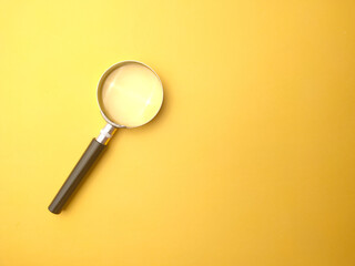 Magnifying glass on a yellow background with copy and text space.
