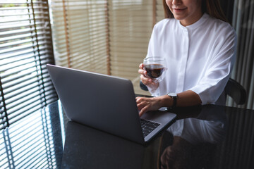 Closeup image of a business woman working on laptop computer while drinking coffee in office