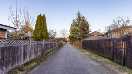 Alley in a residential neighborhood in the city suburbs. Surrey, Greater Vancouver, British Columbia, Canada. Spring Season Sunny Sunset.