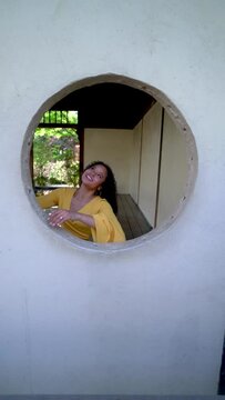 Young Woman Playing in a Round Window