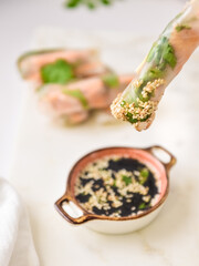 Healthy raw spring rolls with salmon dipping in soy sauce