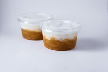 Sweet Rice Noodles with Coconut Cream in a plastic cup on a white table.