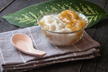 Sweet Rice Noodles with Coconut Cream served in a glass cup on a black wooden table.