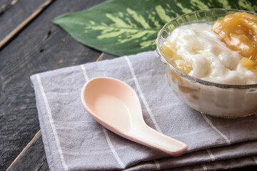 Sweet Rice Noodles with Coconut Cream served in a glass cup on a black wooden table.