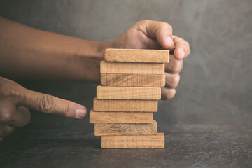 Hand prevent wooden block tower stack not crash or fall. concept of prevention of financial...
