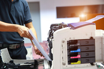 Technician hand open cover photocopier or photocopy to fix paper jam and replace ink cartridges for scanning fax or copy document in office workplace.