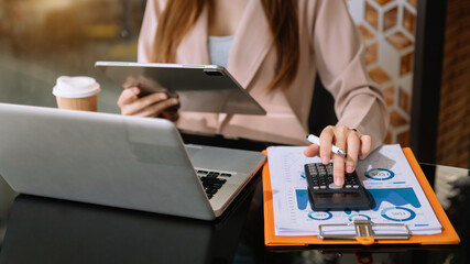 Close up of businesswoman or accountant hand holding pen working  to calculate .on desk about cost at home office.