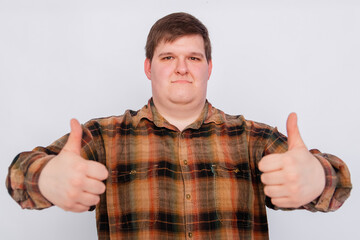 Fototapeta premium Fat guy showing thumbs up with both hands isolated on white background. Young man making a gesture, I like it, great job. Body language, body positivity. 