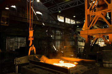 Fototapeta na wymiar Glowing hot liqud metal in industrial foundry