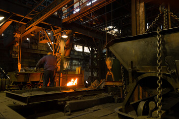 Metallurgist pouring hot molten metal out of furnace