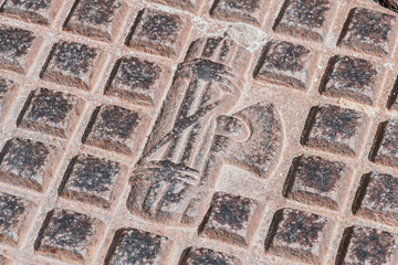 Faded symbol of Fascism on a manhole of the sewer or water system, Mottola, Puglia, Italy