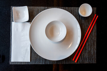Top view of a wooden table with Chinese or Japanese tableware set up for oriental food to be served.