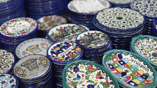 Ceramic plates with traditional national pattern lies on stall in market. Beautiful dishes made of clay - wonderful gift or souvenir for memory about travel in Israel.