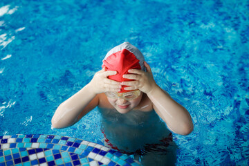A child in a cap and glasses swims dives in the pool