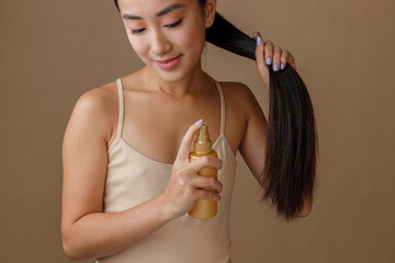 Smiling young woman applying hair spray on her ponytail