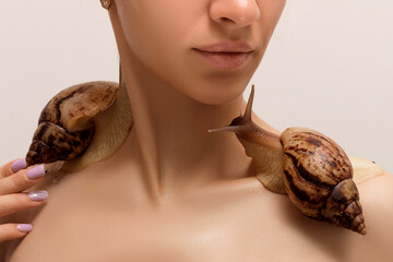 Two large achatina snails crawl over the shoulders of a young woman