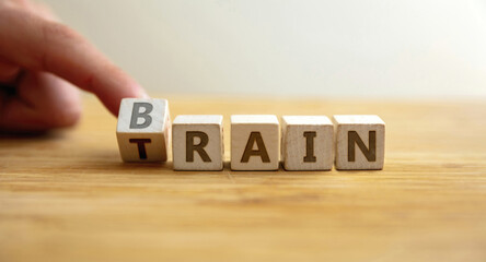 Train your brain concept. Hand flips letter on wooden cube changing the word train to brain.