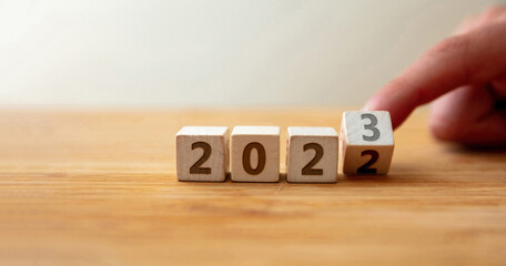 From 2022 to 2023 Happy New Year. Finger flips the last digit on wooden cube changing the year.