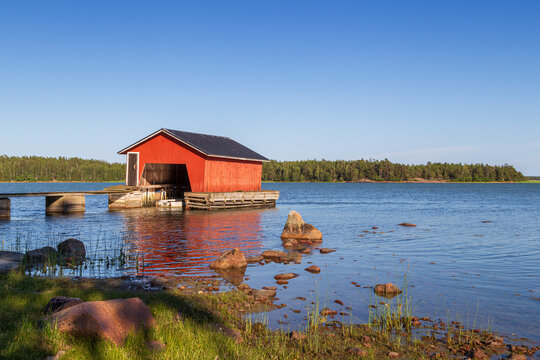 Wooden boathouse, shoreline and ocean in Åland Islands, Finland, on a sunny day in the summer.