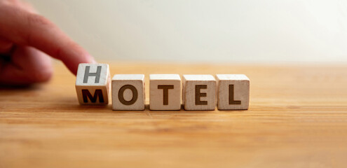 Hotel or motel concept. Hand flips letter on wooden cube changing the word hotel to motel.