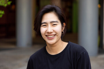 Happy friendly asian non-binary LGBT person smiling to camera - obrazy, fototapety, plakaty