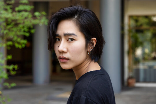 Upset asian non-binary LGBT person looking back with unhappy mood