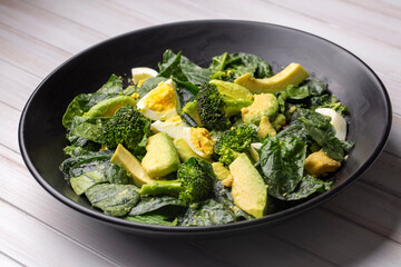 Avocado salad with broccoli, boiled egg in white vintage bowl on light salad