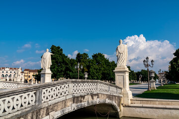 Fototapeta na wymiar Close up on sculpture on bridge of Prato della Valle, square in city of Padua, Veneto, Italy, Europe. Green island at center, Isola Memmia surrounded by canal bordered by two rings of statues. Clouds