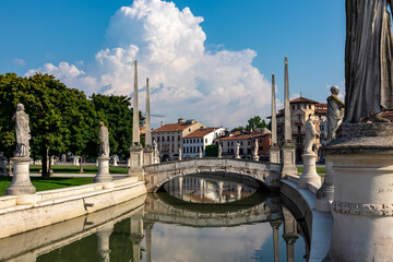 Fototapeta na wymiar Scenic view on bridge of Prato della Valle, square in the city of Padua, Veneto, Italy, Europe. Green island at center, Isola Memmia surrounded by canal bordered by two rings of statues. Thick clouds