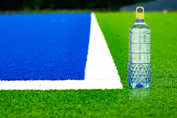 The corner of the artificial turf, the football field, the difference color on the ground , green, white, blue.