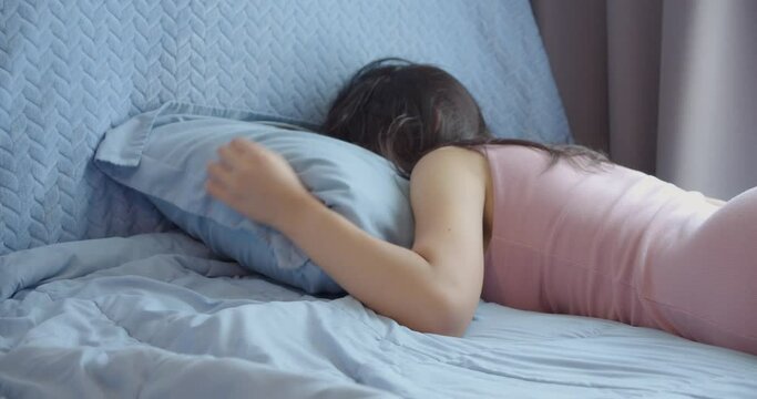 Beautiful Asian woman laying in bed due to tired from work in weekend.lazy woman lying on the bed sleep at home alone.female lacks motivation, is tired and depressed.lifestyle concept.