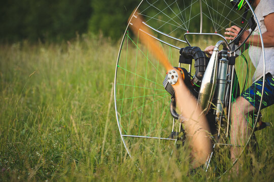 The man warms up the engine and spins the propeller, preparing the paralet with a gasoline engine for flights. Motorized equipment for individual paragliding flights. Extreme sports.
