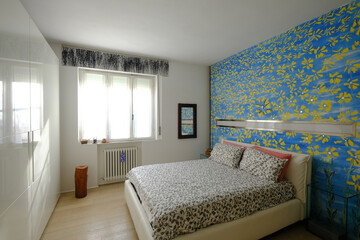 Interior of modern comfortable bedroom with sunflowers on blue color wall