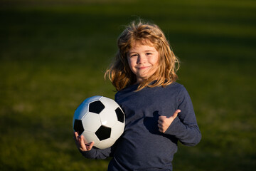 Boy child playing football on football field. Kid playing soccer show thumbs up success sign . Training for sport children.