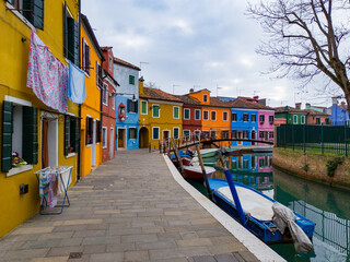 Colorful houses of Burano island. Multicolored buildings on fondamenta embankment of narrow water canal with fishing boats and stone bridge, Venice Province, Veneto Region, Italy. Burano postcard