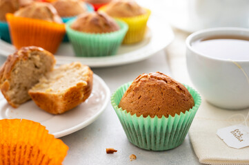Homemade muffin with colorful paper cups, in a plate served with cup of tea