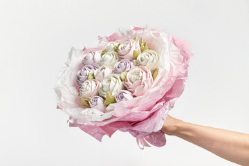Delicate white-pink bouquet of marshmallows in hand on white background