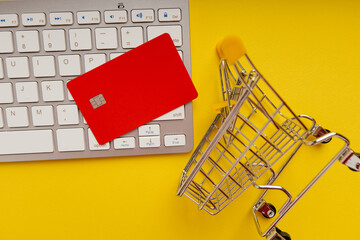 Shopping cart and red credit card on a keyboard close-up. Online shopping concept