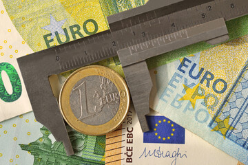 Vernier caliper with euro coin on euro banknotes background - Concept of economy and financial...