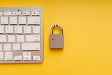 Padlock near computer keyboard on a yellow background. Network Security, data security and...