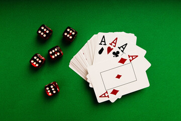Top view of stack of playing cards and red dice on a green table, casino concept