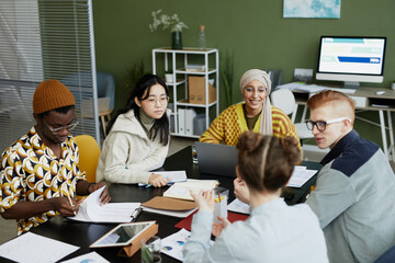 High angle view at diverse creative team collaborating in business meeting while enjoying work on...
