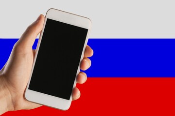 Smartphone with black screen application in hand against the background of the Russian flag.